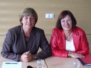 Zwei lächelnde Frauen an einem Tisch zeigen Haltung