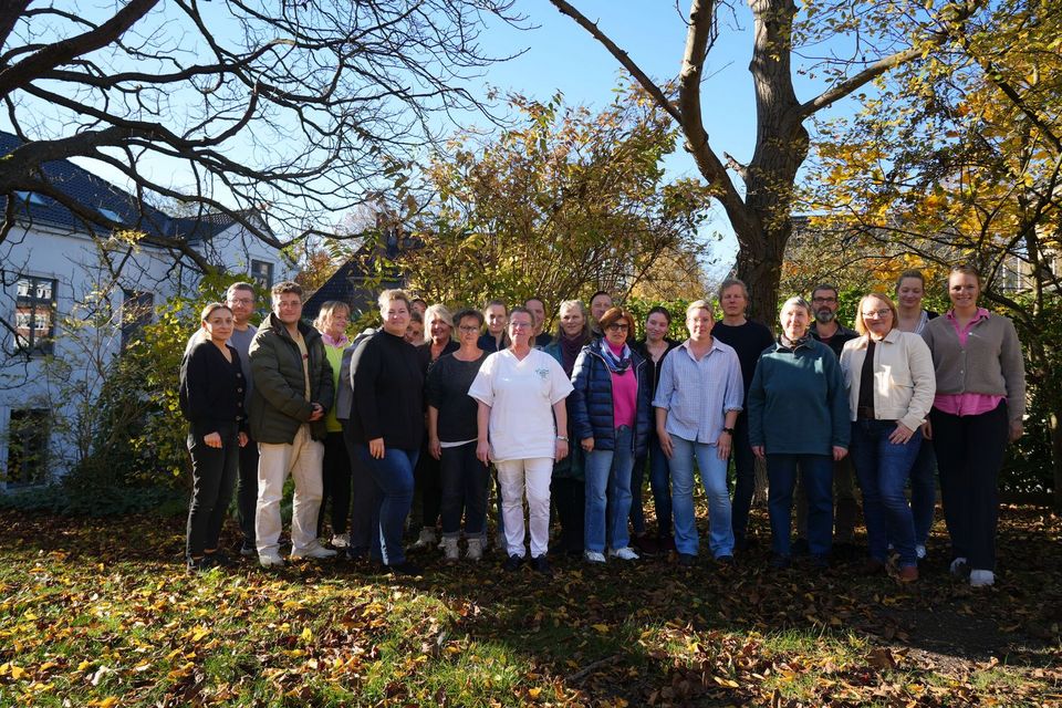 Gruppenfoto: 23 Personen stehen vor einer Hecke. Die Praxisanleiter*innen mit Angela Scheibe (5. v.r.).